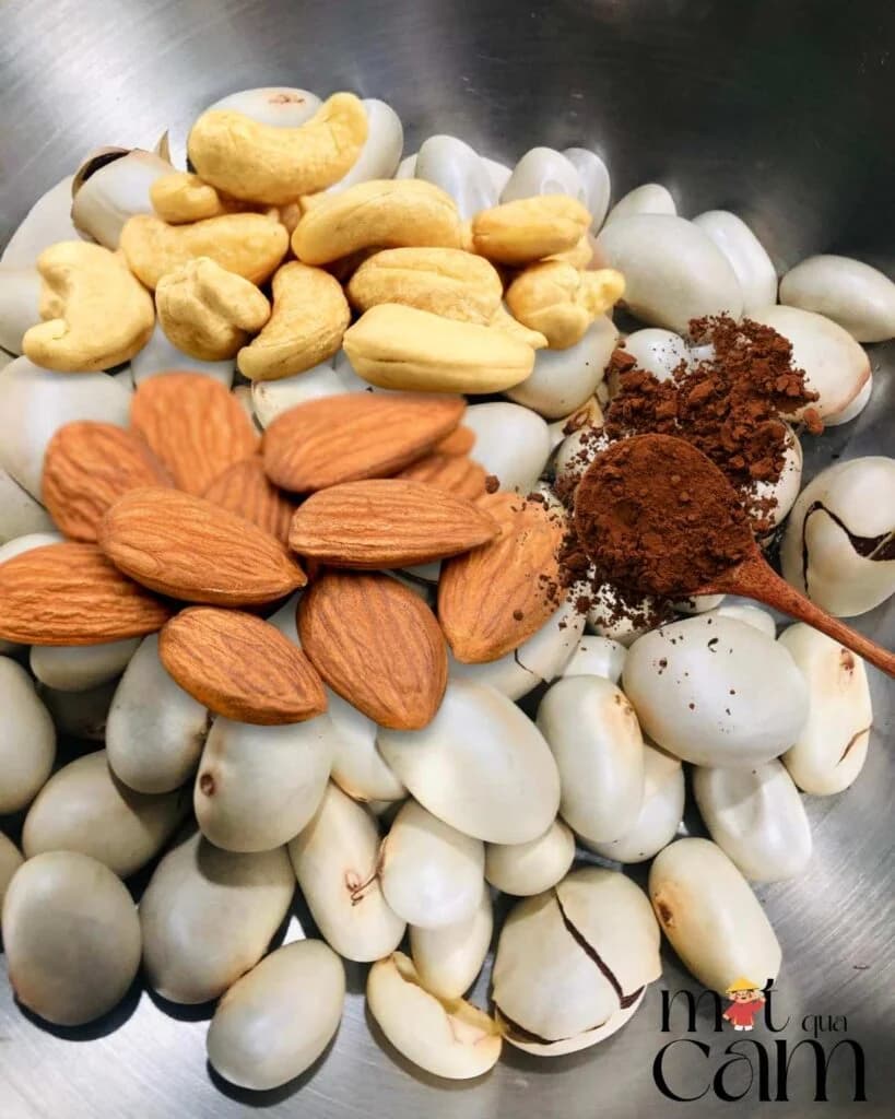 Hạt điều, hạnh nhân, một thìa bột cacao và hạt mít trắng trong nồi inox