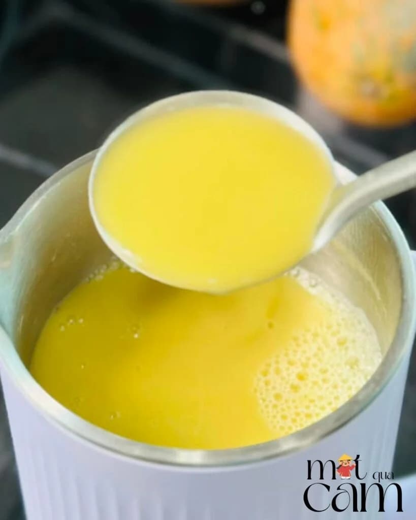 Thìa múc sữa bí đỏ vàng sánh từ cối xay