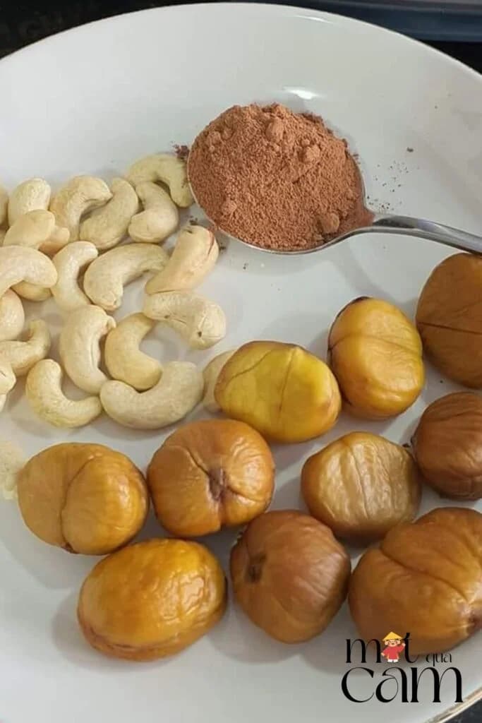 Đĩa hạt điều, một thìa bột cacao và hạt dẻ đã bóc vỏ