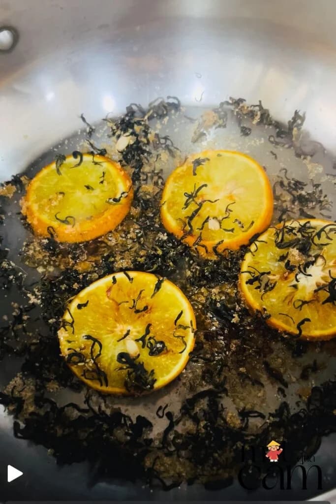 Những lát cam áp chảo cùng lá trà trong chảo inox